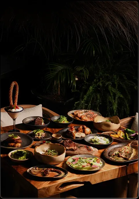 Mesa servida con variedad de platos gourmet y cócteles