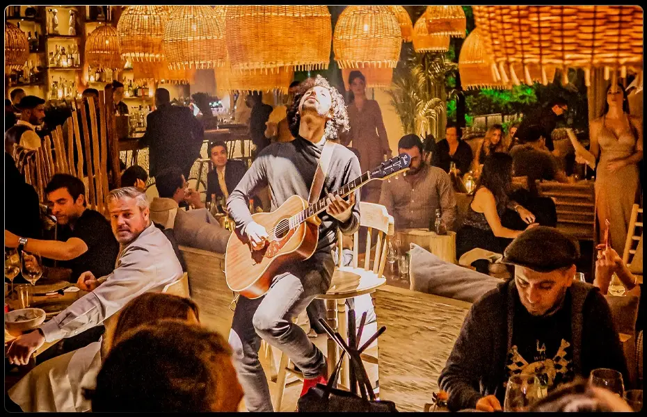 Músico tocando guitarra en un restaurante concurrido de Polanco