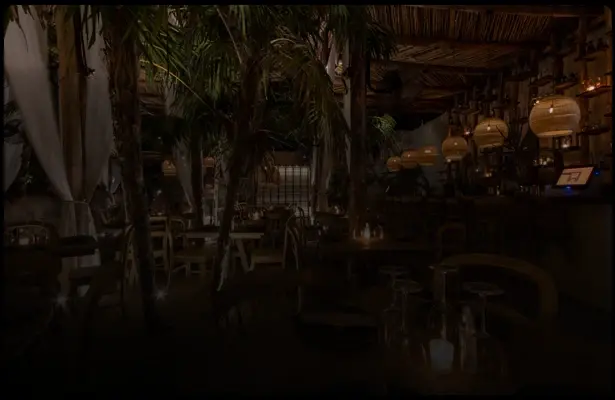 Restaurante nocturno con palmeras y luces tenues en Tulum