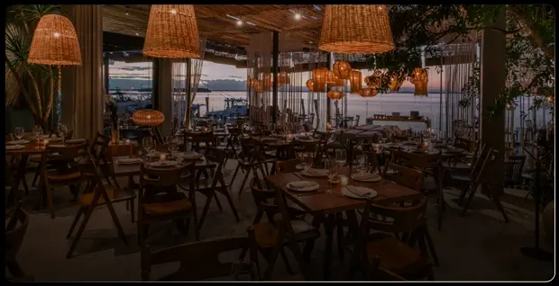 Interior de restaurante de Cancún con vistas a la laguna en el atardecer.