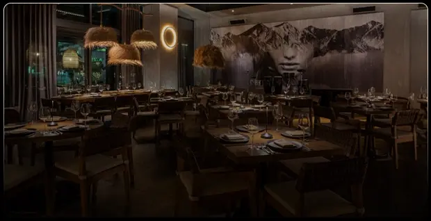 Interior de restaurante Rosa Negra Miami con iluminación tenue y mural artístico.