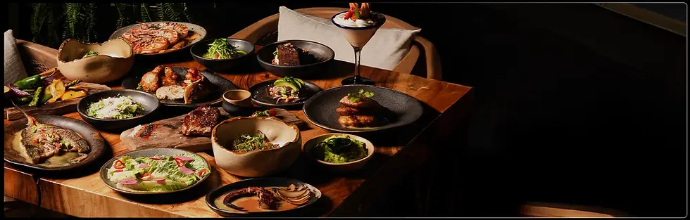 Mesa servida con variedad de platos gourmet y cócteles