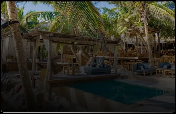 Alberca rodeada de palmeras y hamacas en Tulum