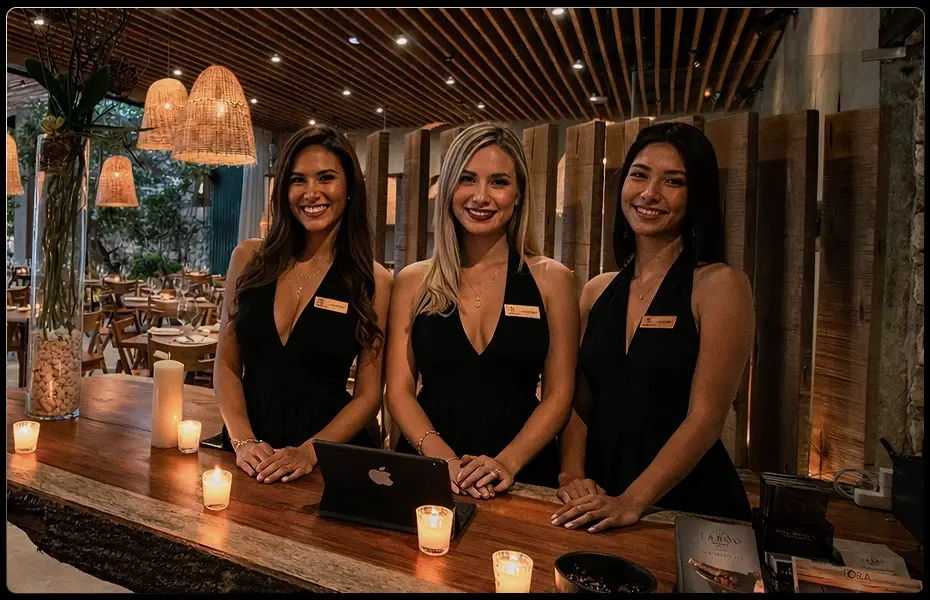 Three smiling hosts at a restaurant reception
